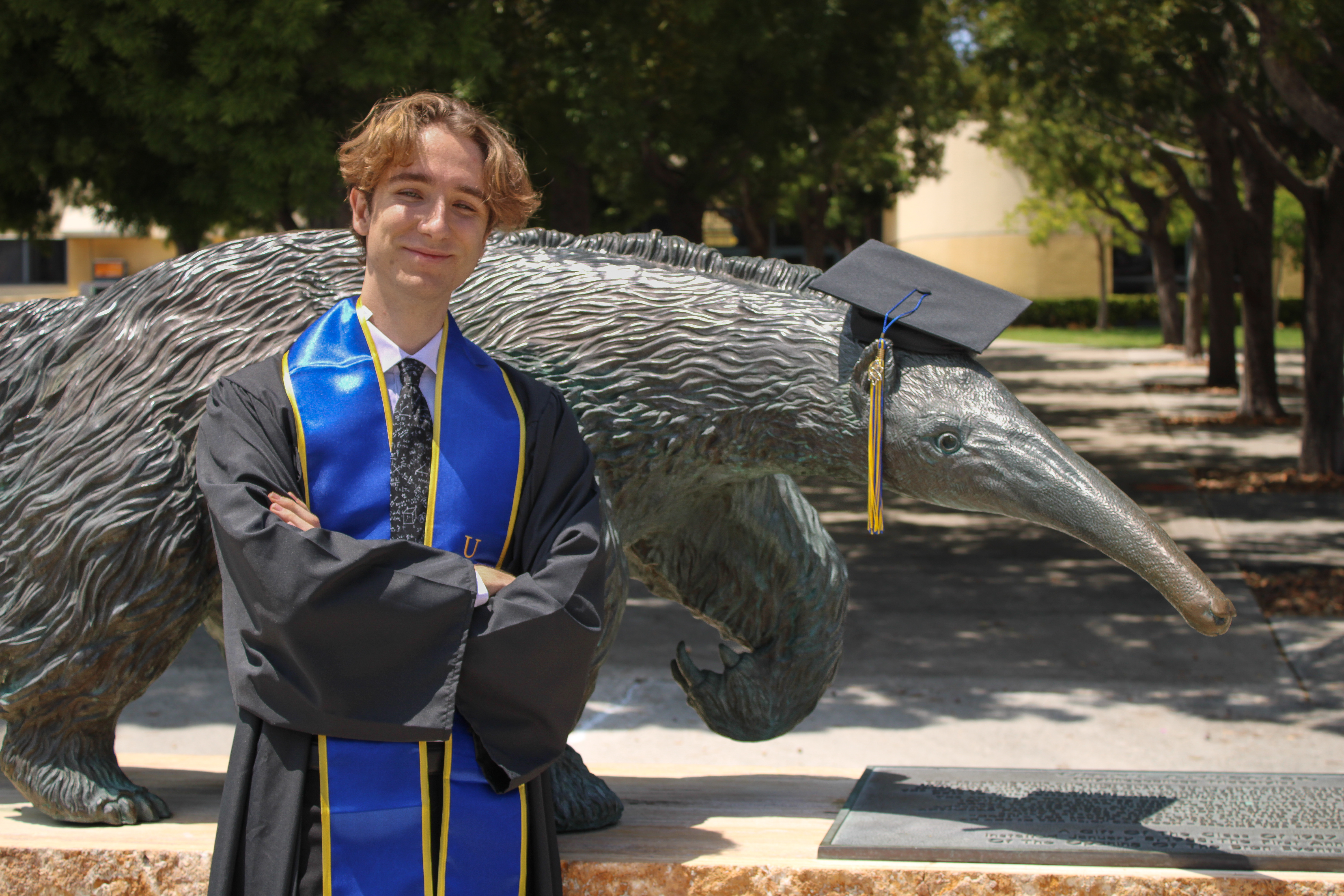 Photo of me in my graduation gown, standing in fronf of an anteater sclupture